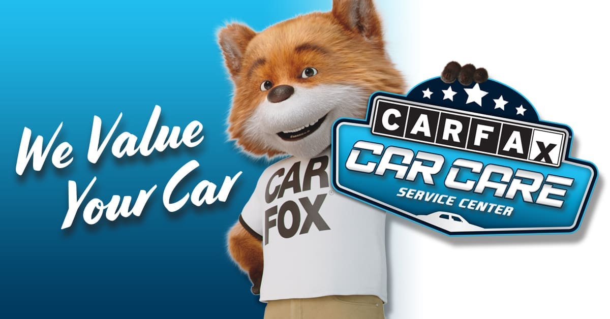 CarFax Car Fox standing in front of image that says "We Value Your Car" holding the CarCare Service Center Logo. CarFax undercoating rust prevention vehicle service history reporting.